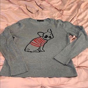 A French bulldog wearing a sweater on a sweater.